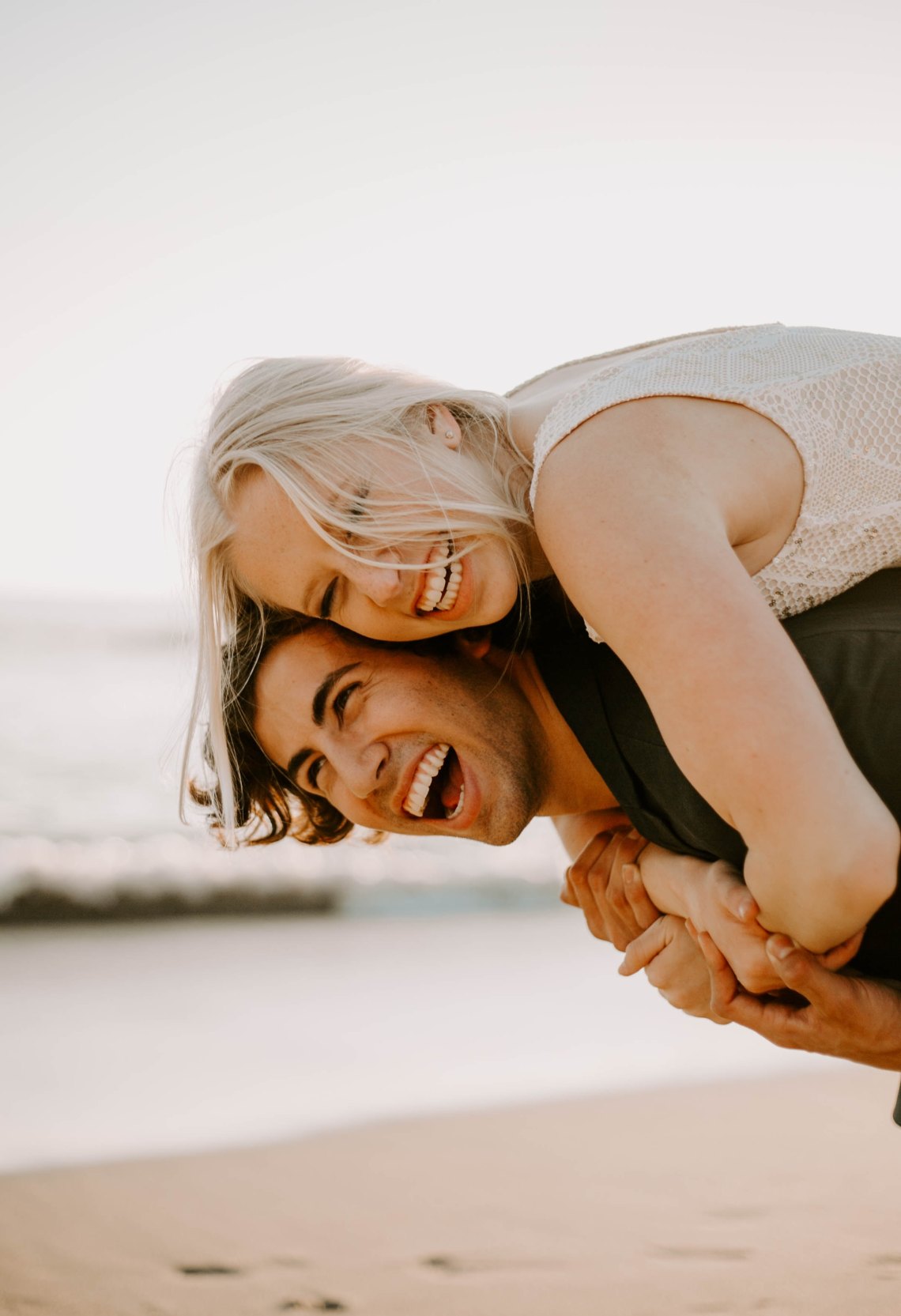 couple snuggling on the beach and laughing