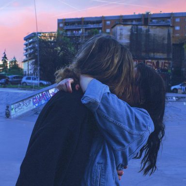 Couple kissing, embracing surrounded by concrete and graffiti