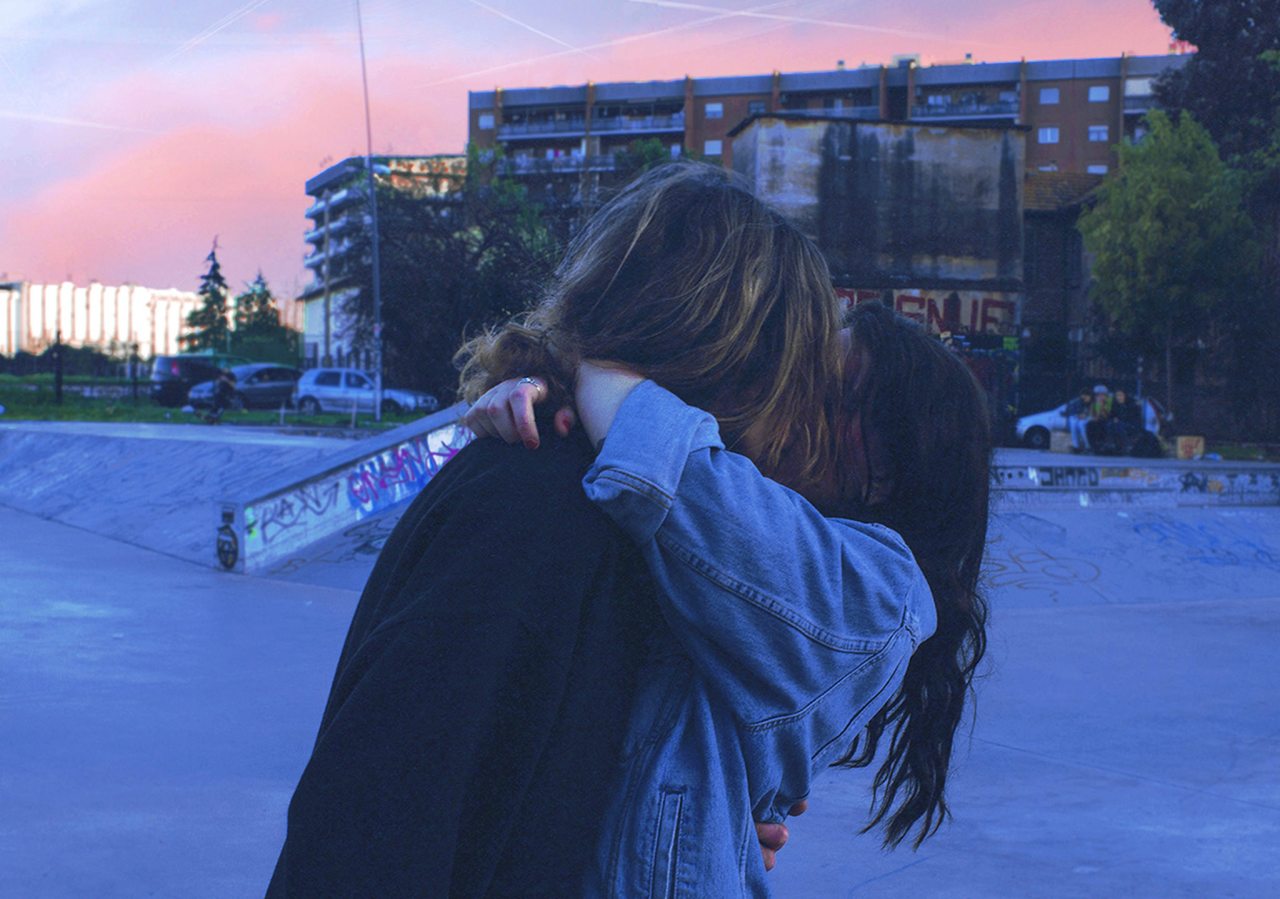 Couple kissing, embracing surrounded by concrete and graffiti