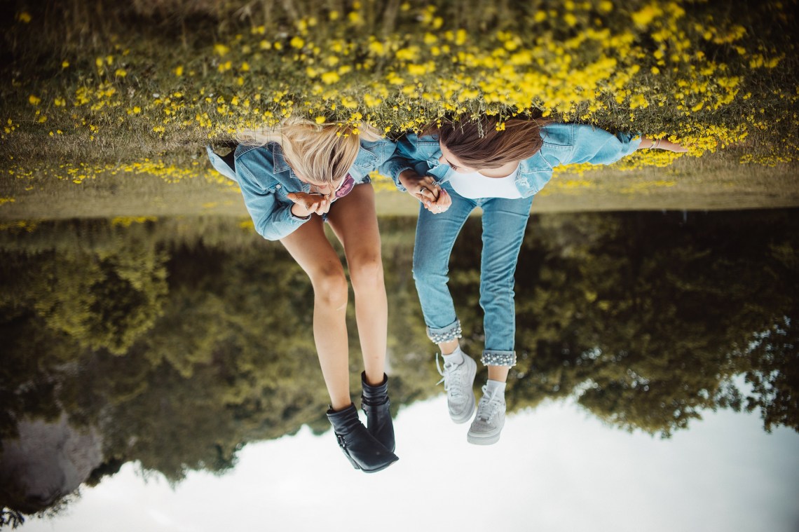 Upside down best friends laying in the grass with yellow flowers, being young, enjoying summer, happy best girl friends, friendship sisters, holding hands, hanging out, nature outdoors happy good times