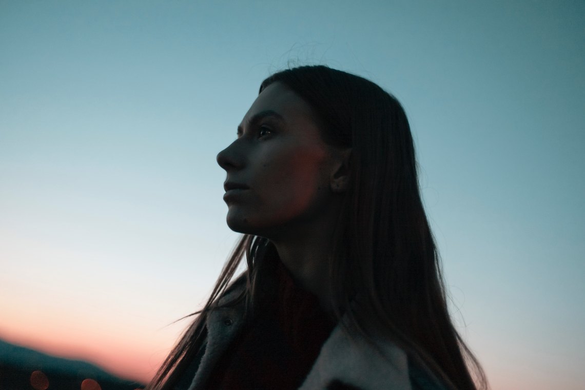 woman standing looking pensive at sunset