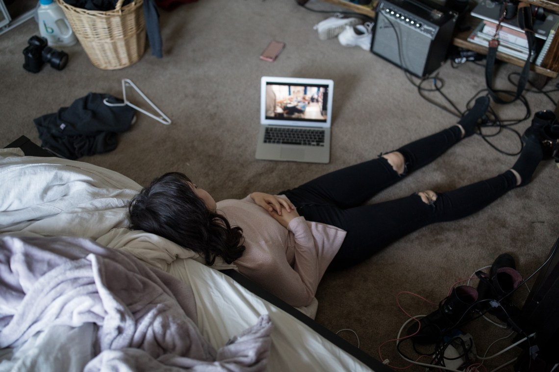 woman watching laptop in disorganized room