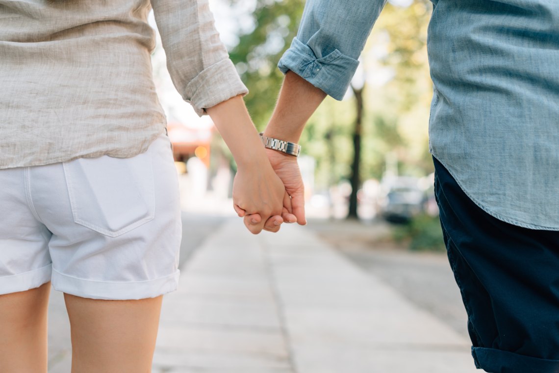 A girl and a boy hold hands while walking