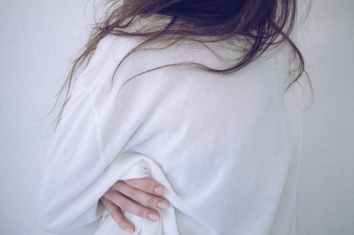 Girl faces away from the camera, hugging herself