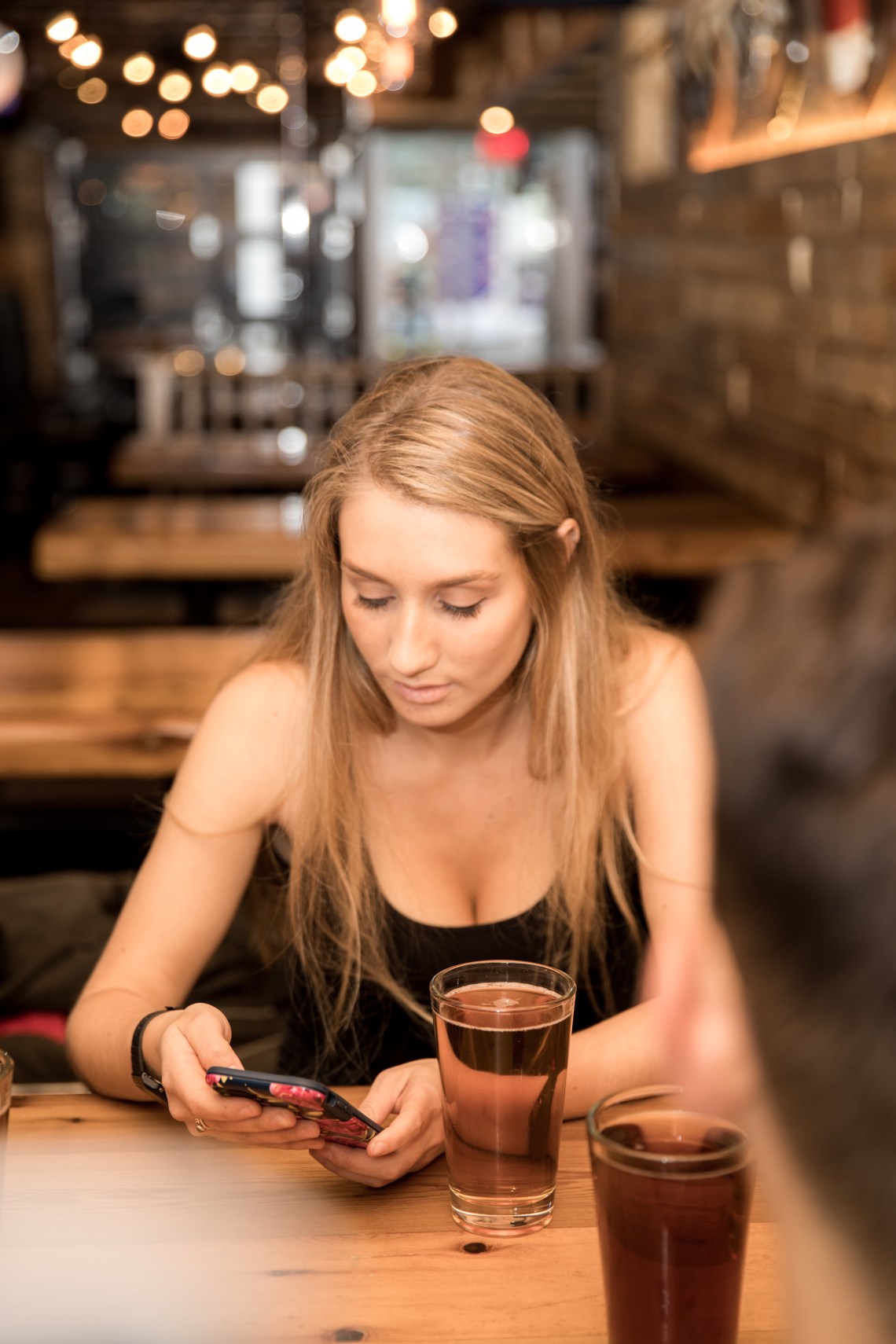 woman drinking beer and checking cell phone