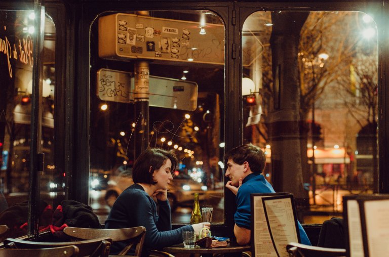 A couple sit together in a restaurant, on a date