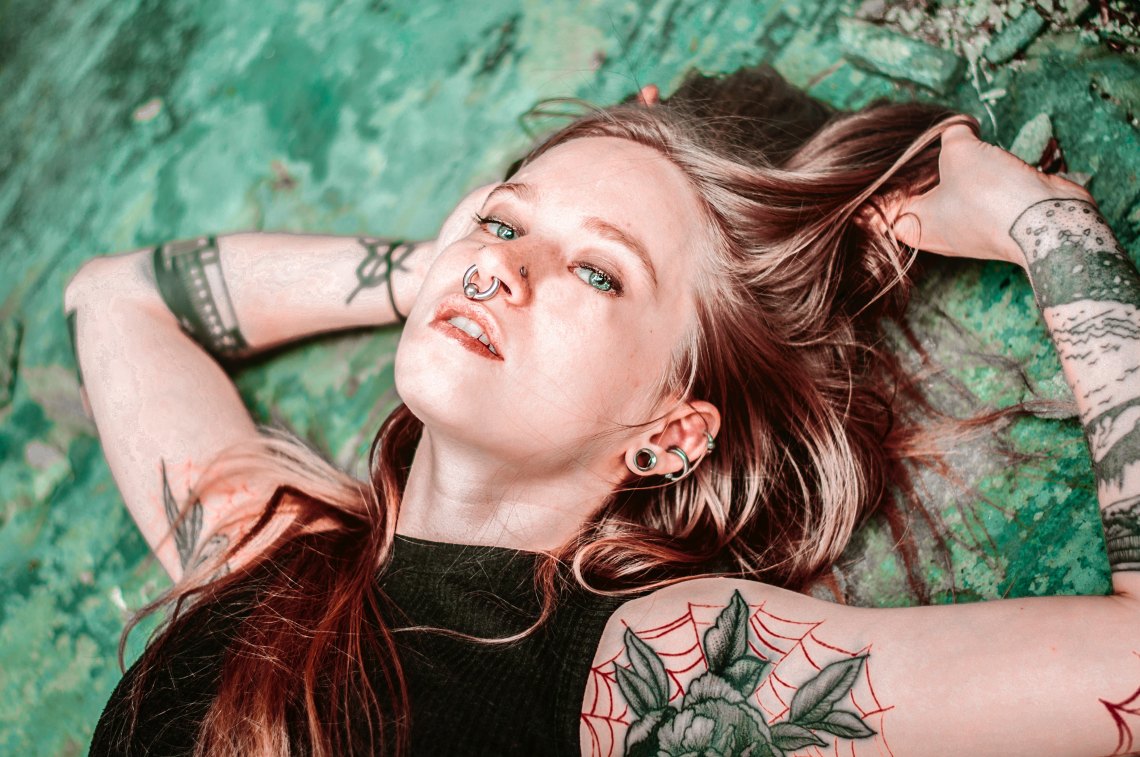 A woman with piercings (including a conch piercing) lying down on the grass