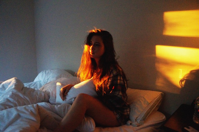 woman sitting in bed at sunrise