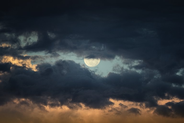 The moon peaking out behind clouds