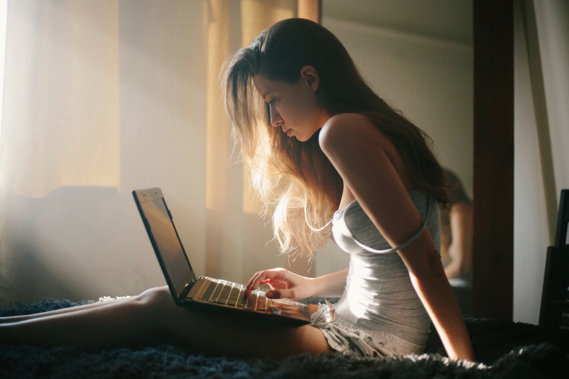 woman sitting on bed on laptop