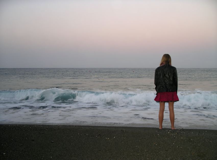 woman standing on shore looking at sea