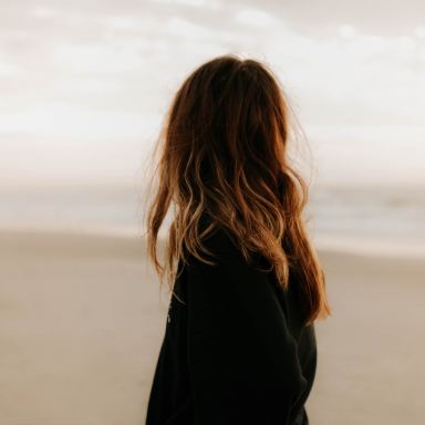 woman in black jacket standing on beach during daytime