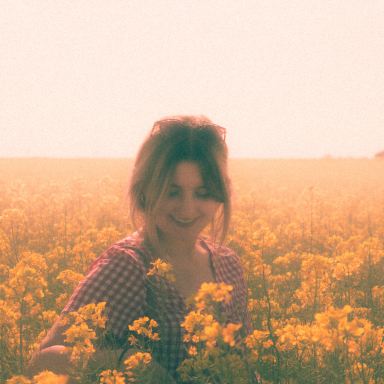 woman in black and white long sleeve shirt standing on yellow flower field during daytime