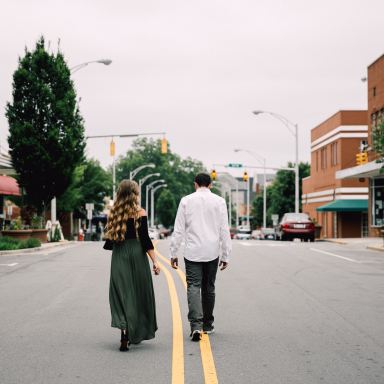 man and woman walking in the middle of the road