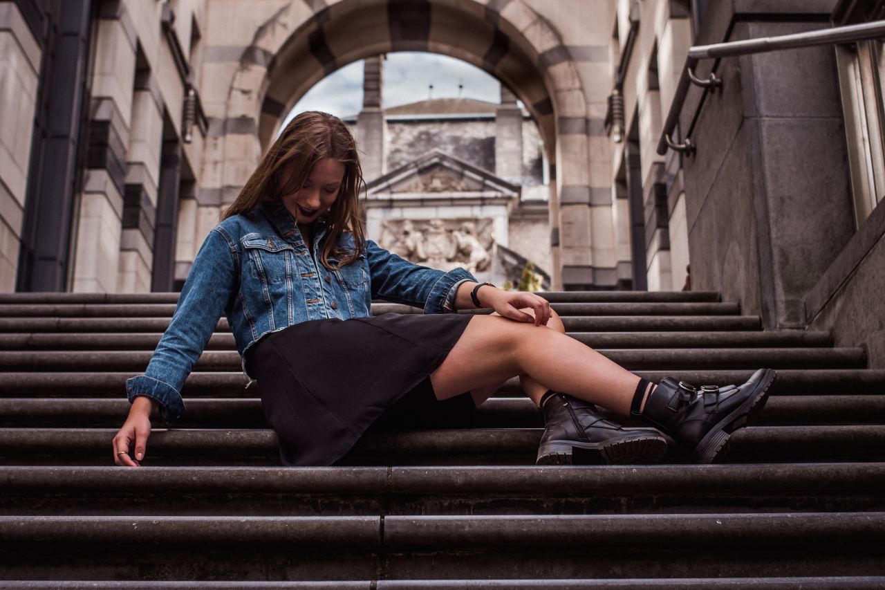 woman wearing blue denim jacket sitting on stairs