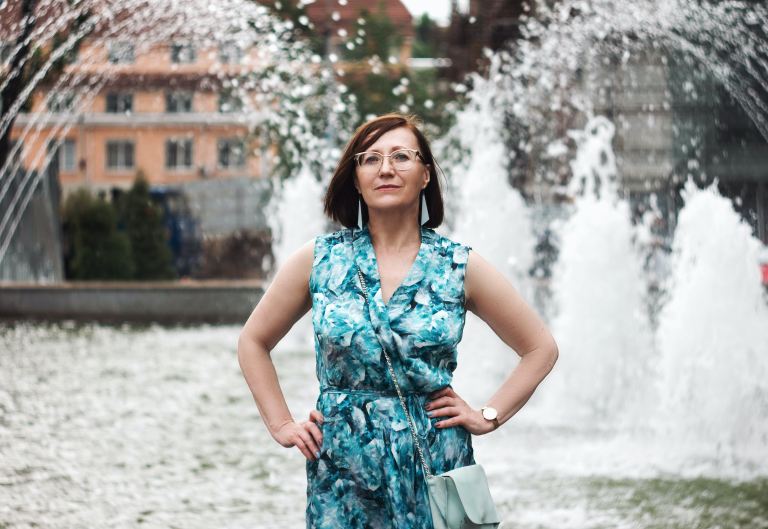 woman in blue and white floral sleeveless dress standing on snow covered ground during daytime