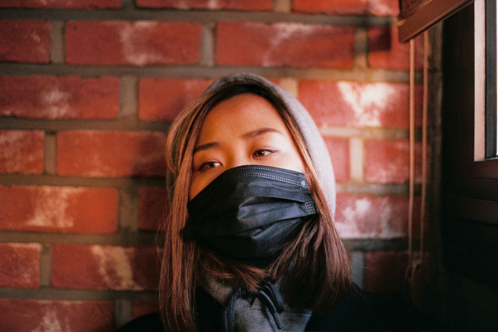 woman in black leather jacket covering face with black scarf