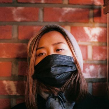 woman in black leather jacket covering face with black scarf
