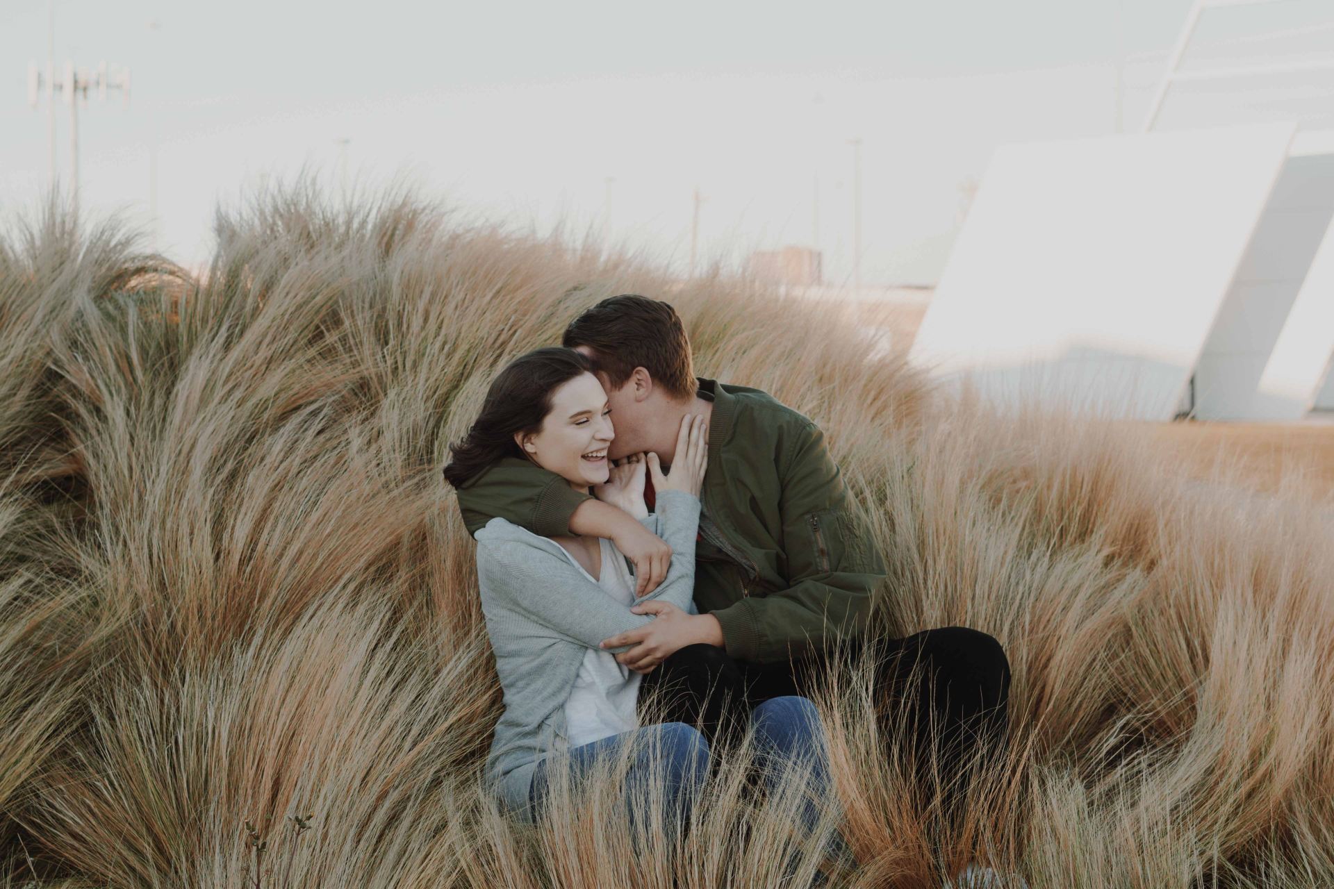 man whispering on womans ear on brown grass field