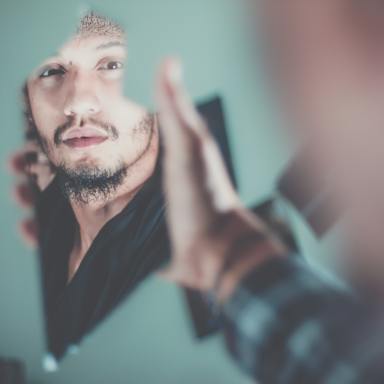 selective focus photography of man's reflection in broken mirror
