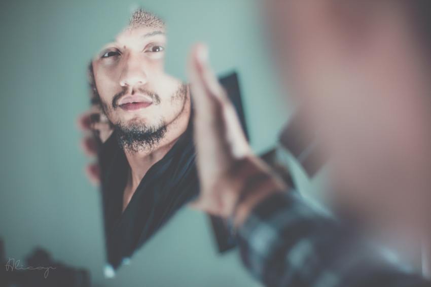 selective focus photography of man's reflection in broken mirror