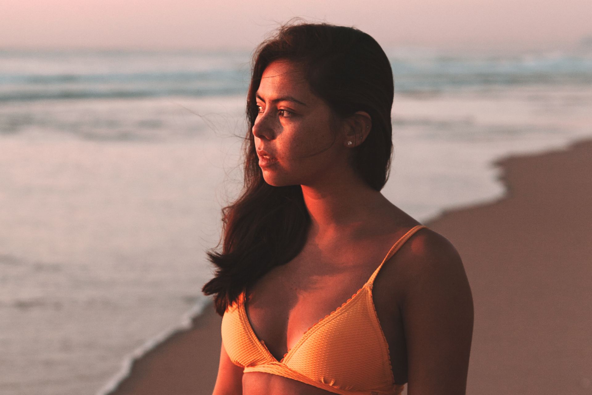 woman in white bikini top standing on beach during sunset