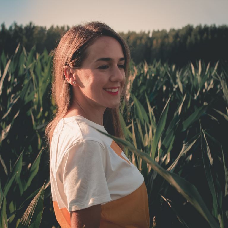 woman smiling beside green leaves during golden hour