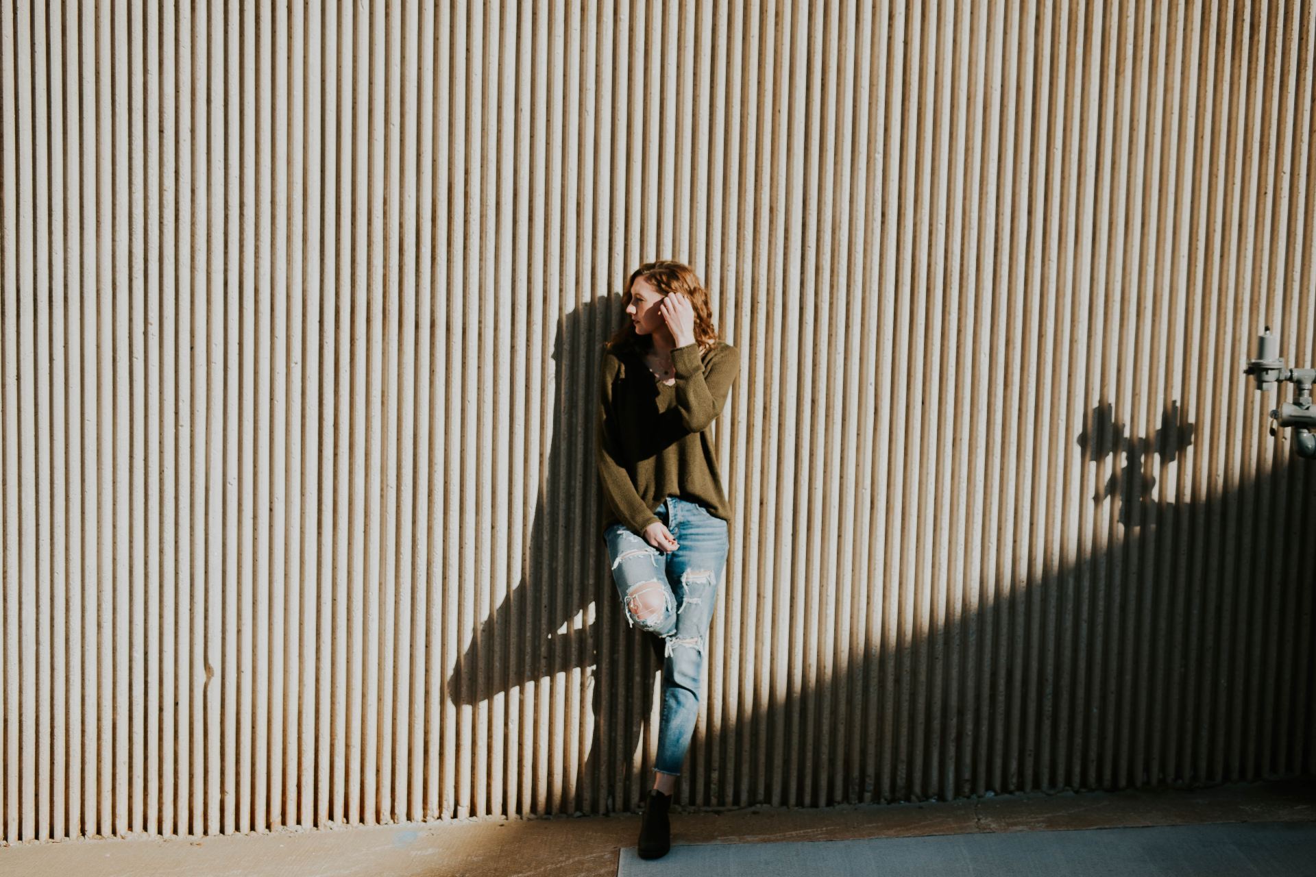 woman leaning on beige wall with shadow at daytime