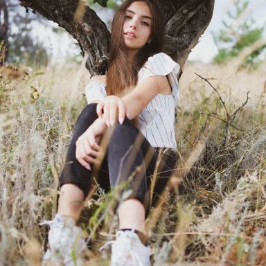 woman in white shirt and black skirt sitting on tree trunk