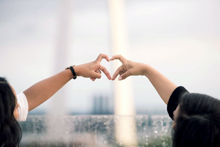 two person doing heart hand sign during daytime