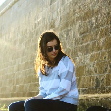 woman sitting beside brown concrete wall