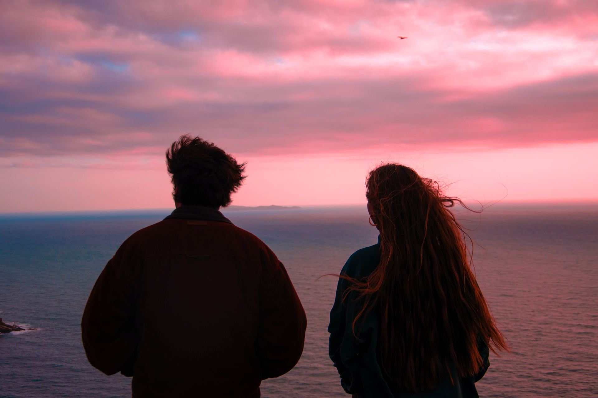 couple standing on seashore during sunset