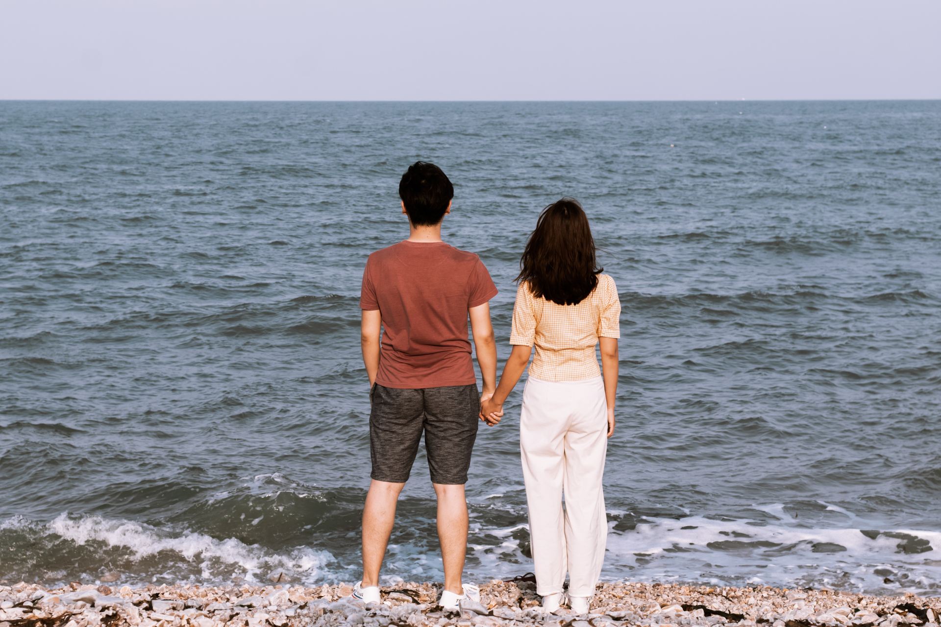 man and woman standing infront of ocean water at daytime