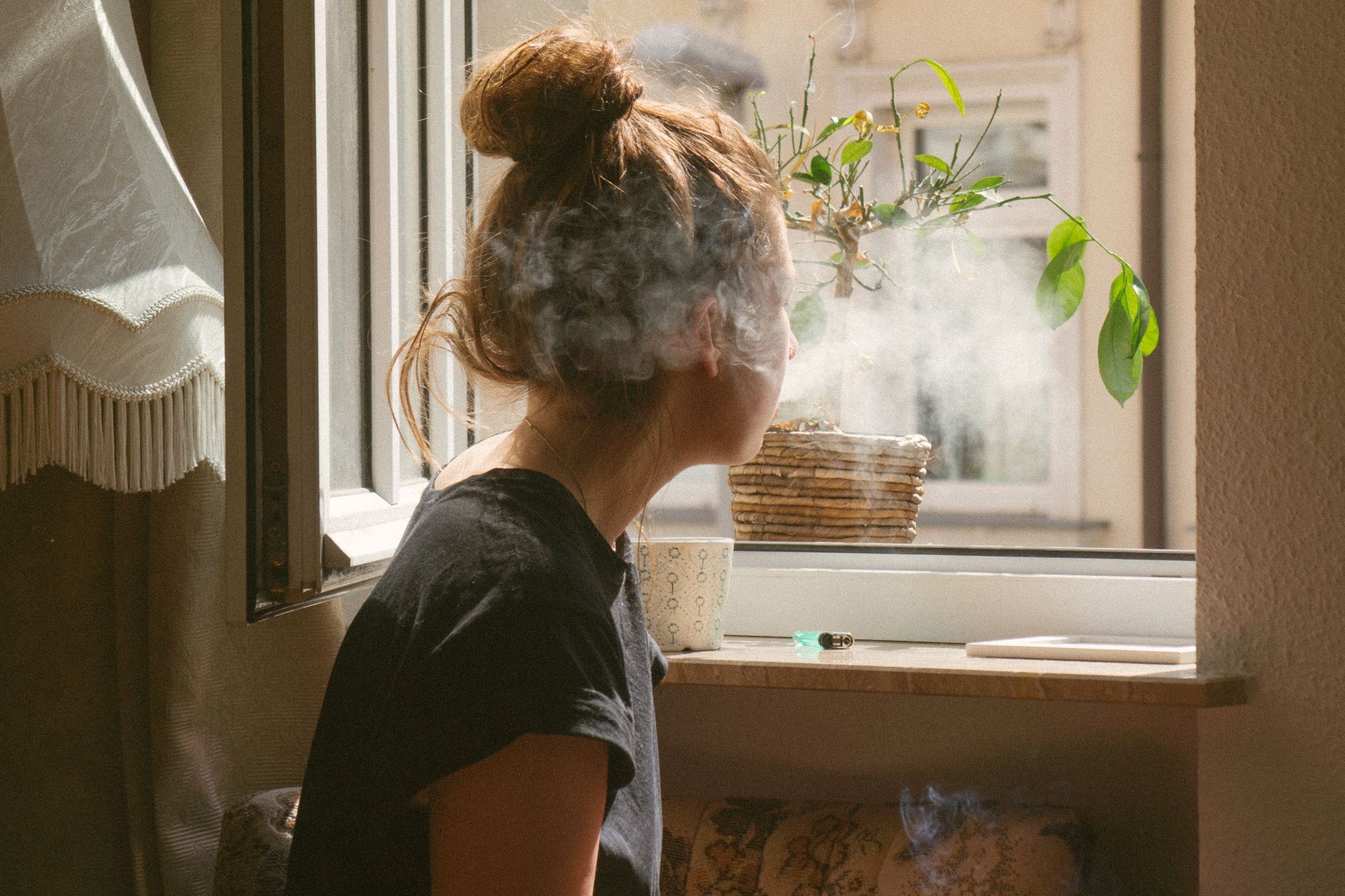 woman smoking while look through the window