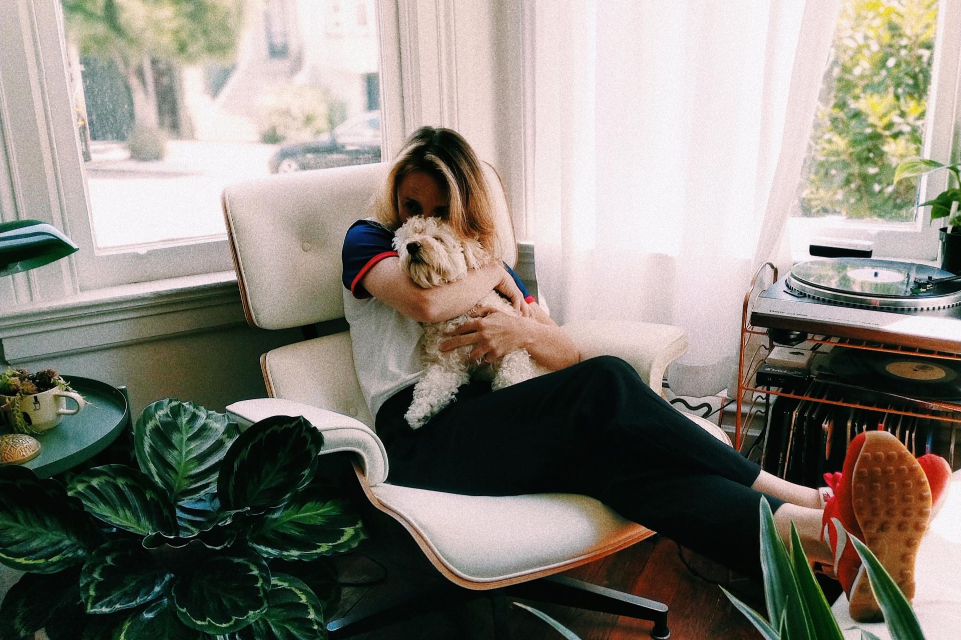 woman kissing dog while sitting on chair
