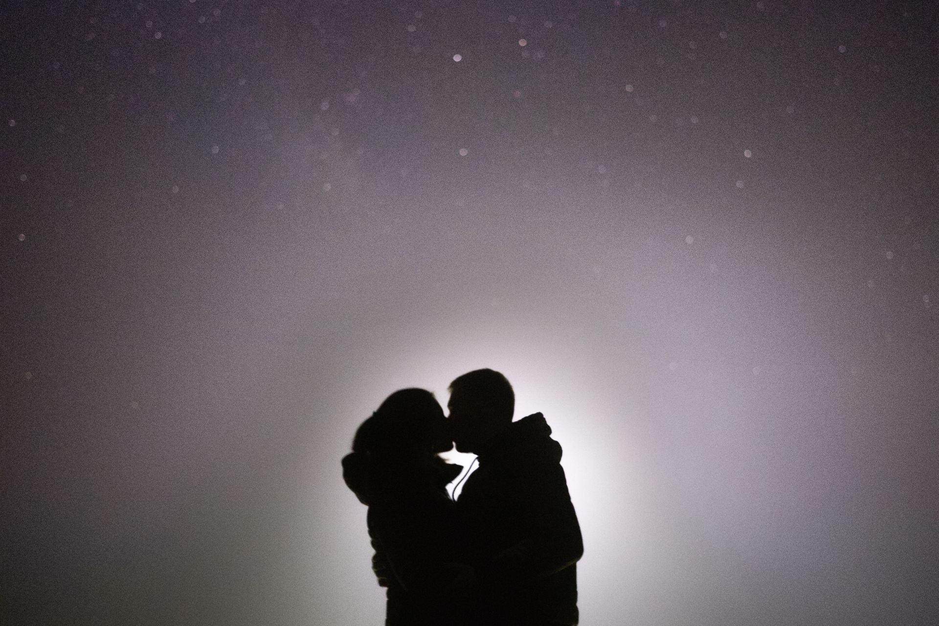 silhouette of man and woman kissing under starry night