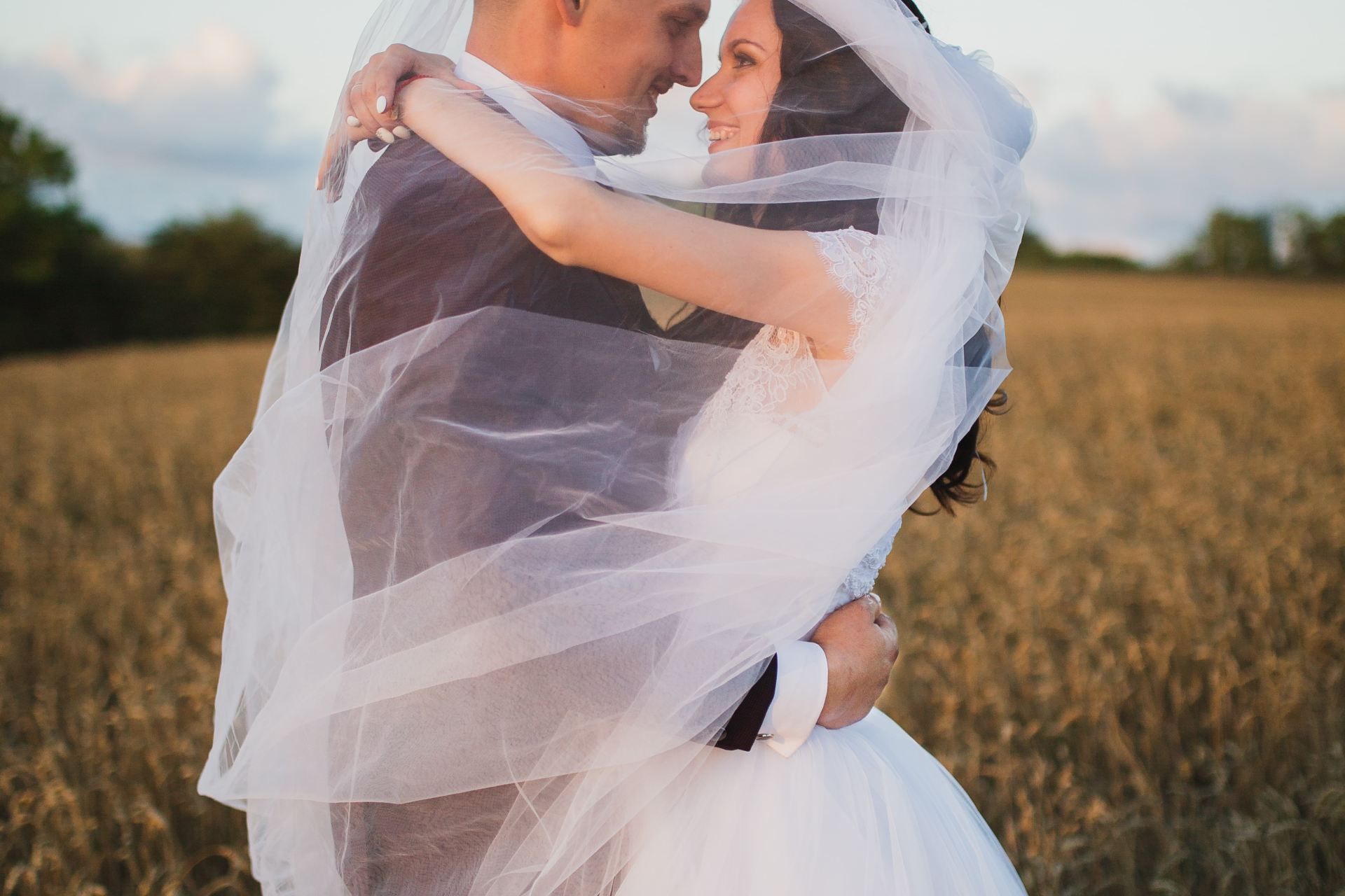 smiling newly wed couple about to kiss in green field