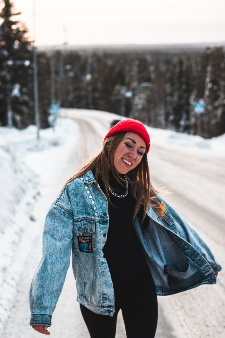 woman in blue denim jacket and red knit cap standing on snow covered ground during daytime