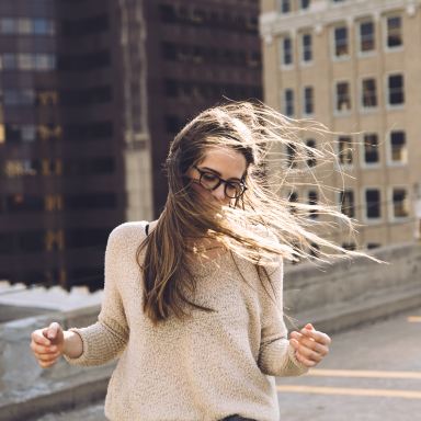 woman standing near building with hair being blown by wind