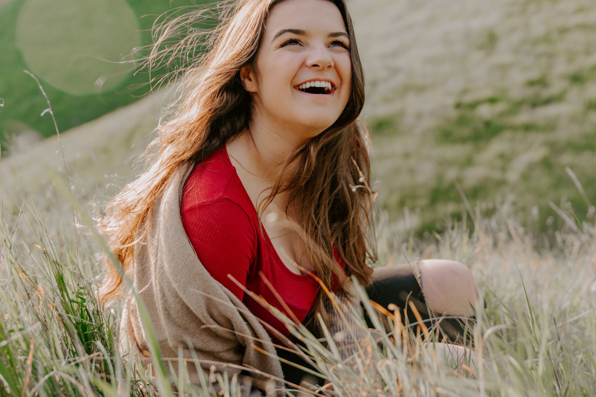 depth photography of woman in red top sitting on green grass