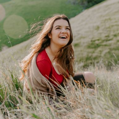 depth photography of woman in red top sitting on green grass