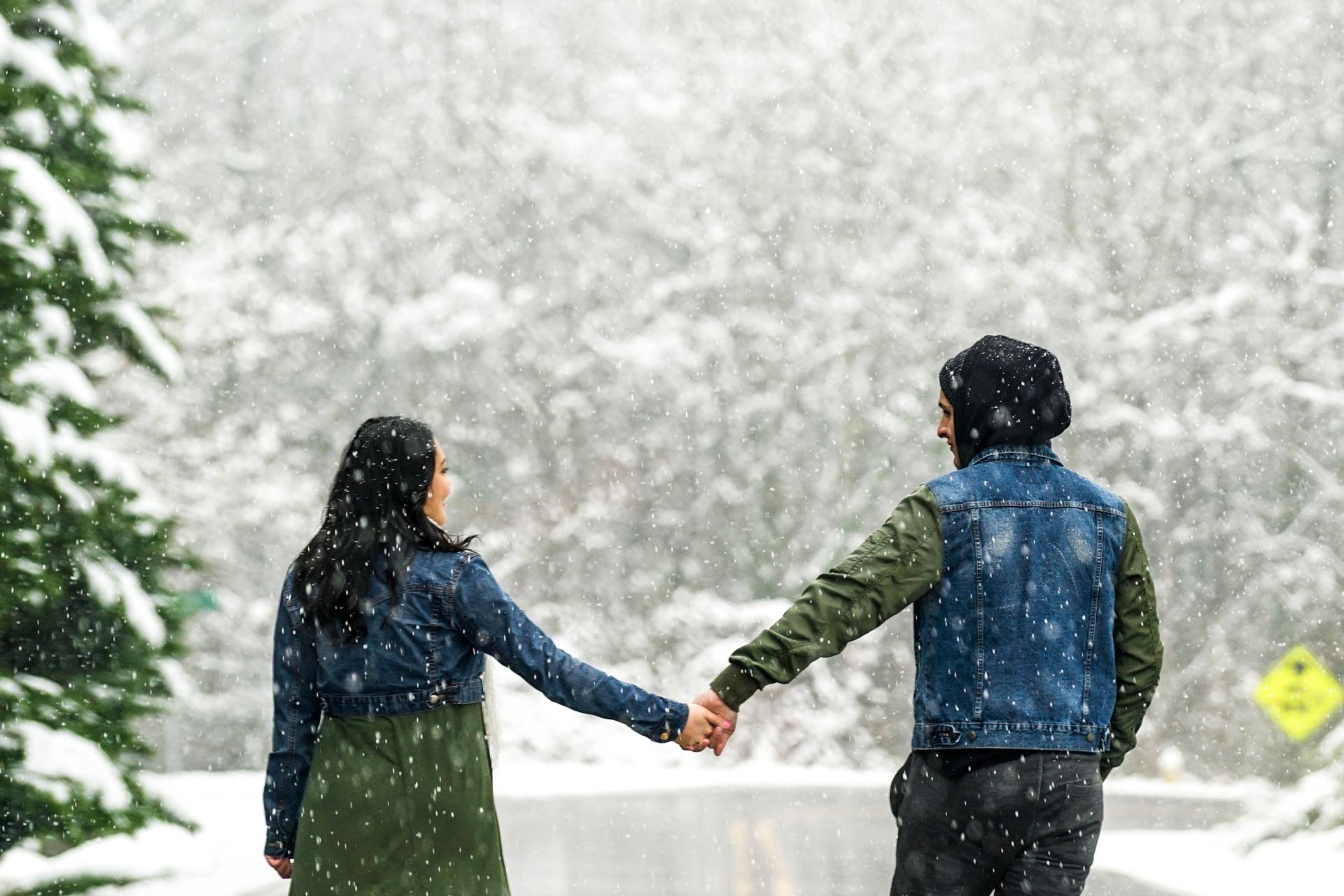 couple holding hands on wet road during daytime