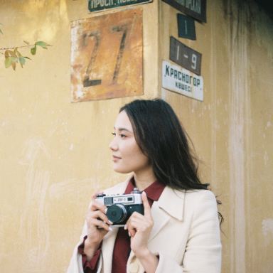 woman in white coat holding gray camera