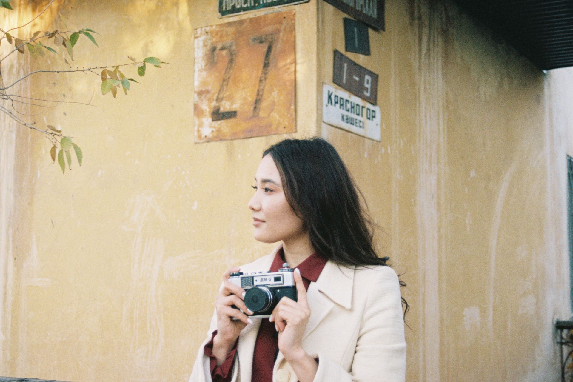woman in white coat holding gray camera