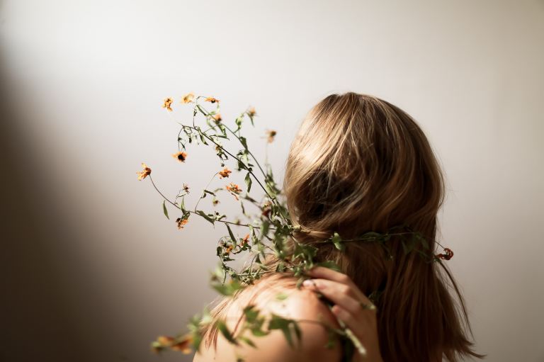 blonde woman holding green and yellow petaled flowers
