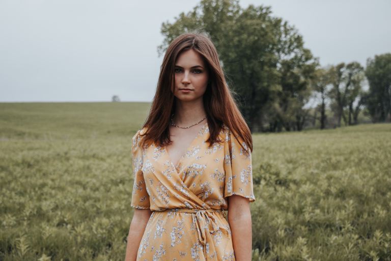 woman in yellow floral dress standing on green grass field during daytime