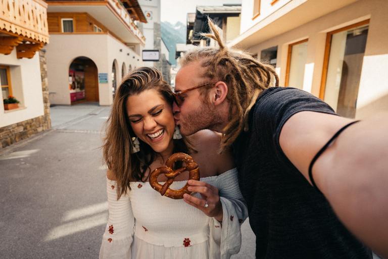 man and woman smiling while holding brown heart shaped pretzel