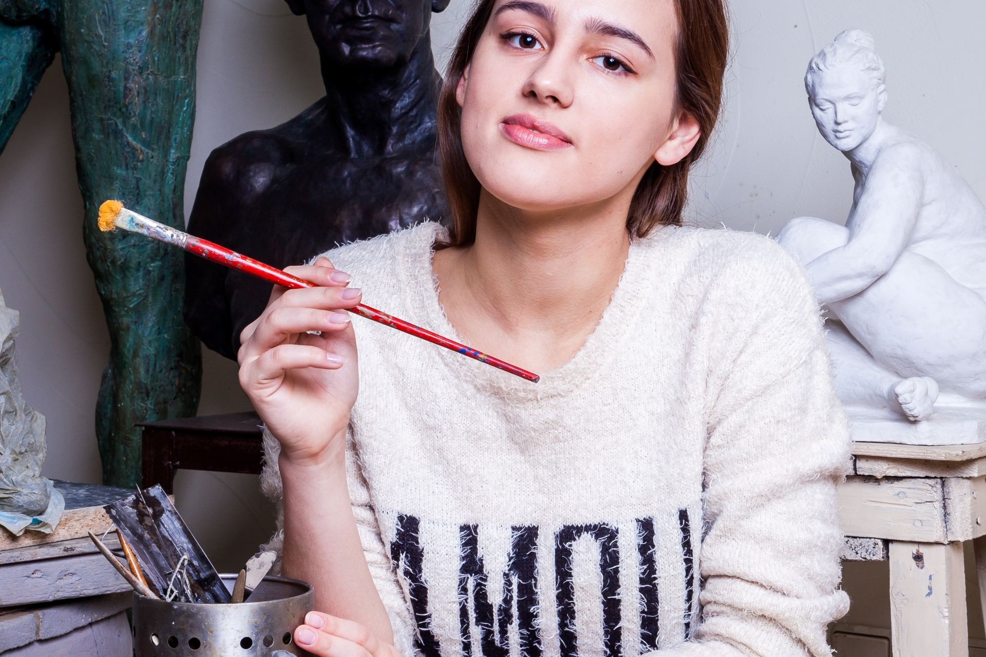 woman leaning on table and holding paint brush