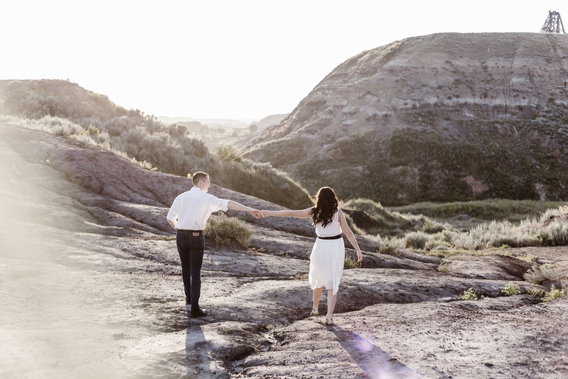 couple holding hands while walking along the rocky coastline