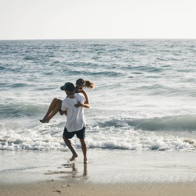 man carrying woman on seashore